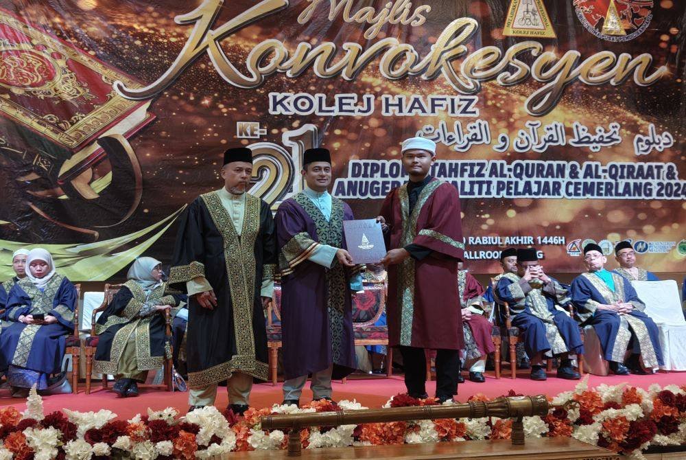 Mohammad Fahmi (tengah) menyampaikan anugerah kecemerlangan kepada salah seorang pelajar pada Majlis Konvokesyen Kolej Hafiz ke-21 pada Sabtu.