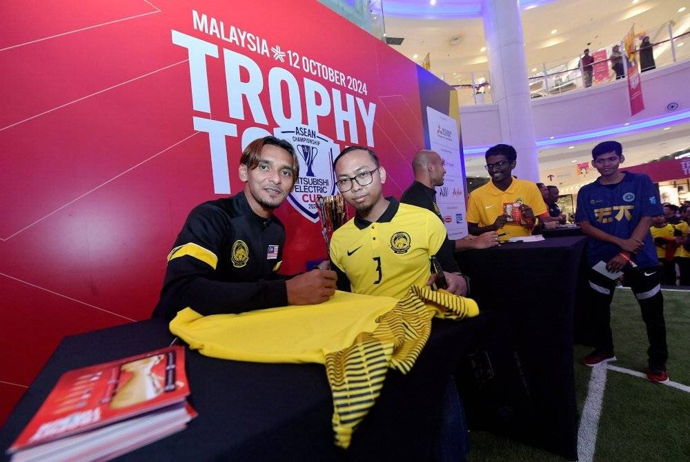 Amri Yahya (kiri) beramah mesra bersama penyokong Harimau Malaya yang hadir ke Jelajah Piala AFF di sebuah pasar raya di Seksyen 13 Shah Alam hari ini. Foto Bernama