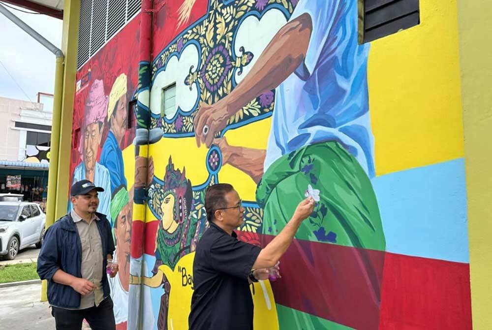 Azman (kanan) dan Muhamad Hanif (kiri) memberi sentuhan akhir bagi menyiapkan lukisan mural di Rantau Panjang.