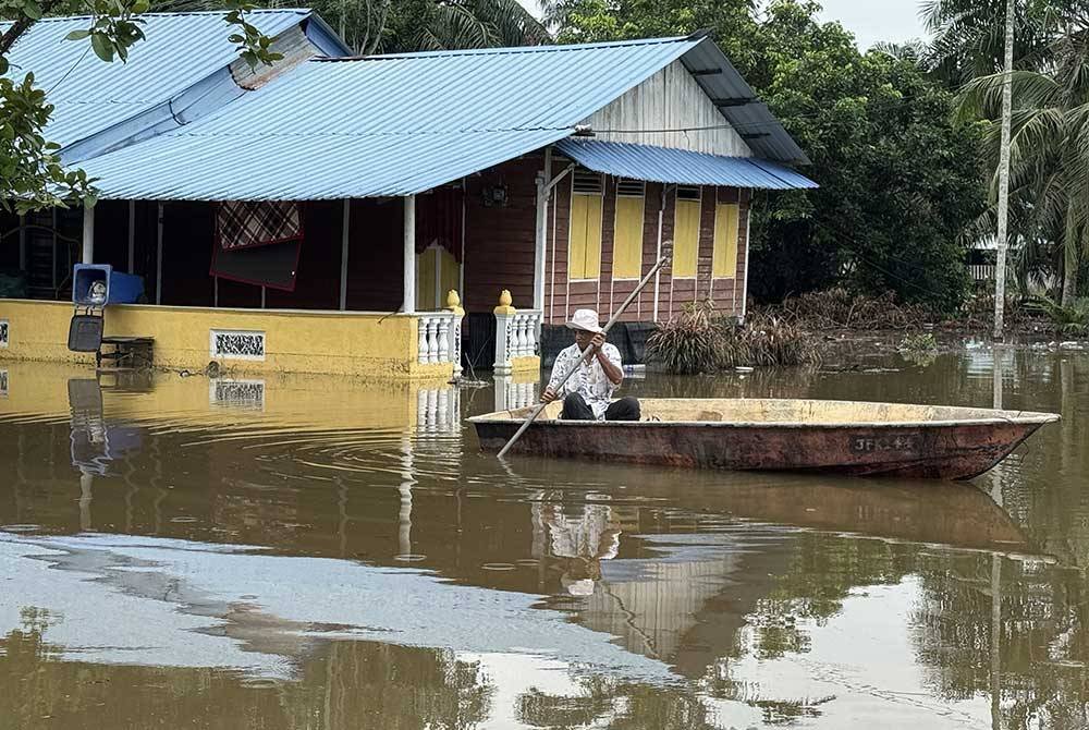 Penduduk Kampung Sungai Linau, Simpang Renggam, Misri Salamon, 63, perlu menggunakan sampan untuk meninjau keadaan rumahnya yang ditenggelami banjir sejak Sabtu lepas. Foto Bernama