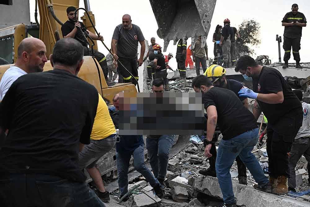 Petugas pertahanan awam Lubnan mengangkat mayat dari bawah runtuhan di tapak serangan udara Israel di perkampungan Gunung Lebanon di Maaysra, timur bandar pantai Byblos pada 12 Oktober 2024. Foto AFP