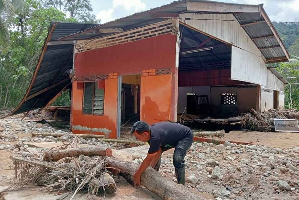 Mohd Naim mengangkat sisa kayu yang hanyut akibat banjir melanda daerah Baling baru-baru ini.