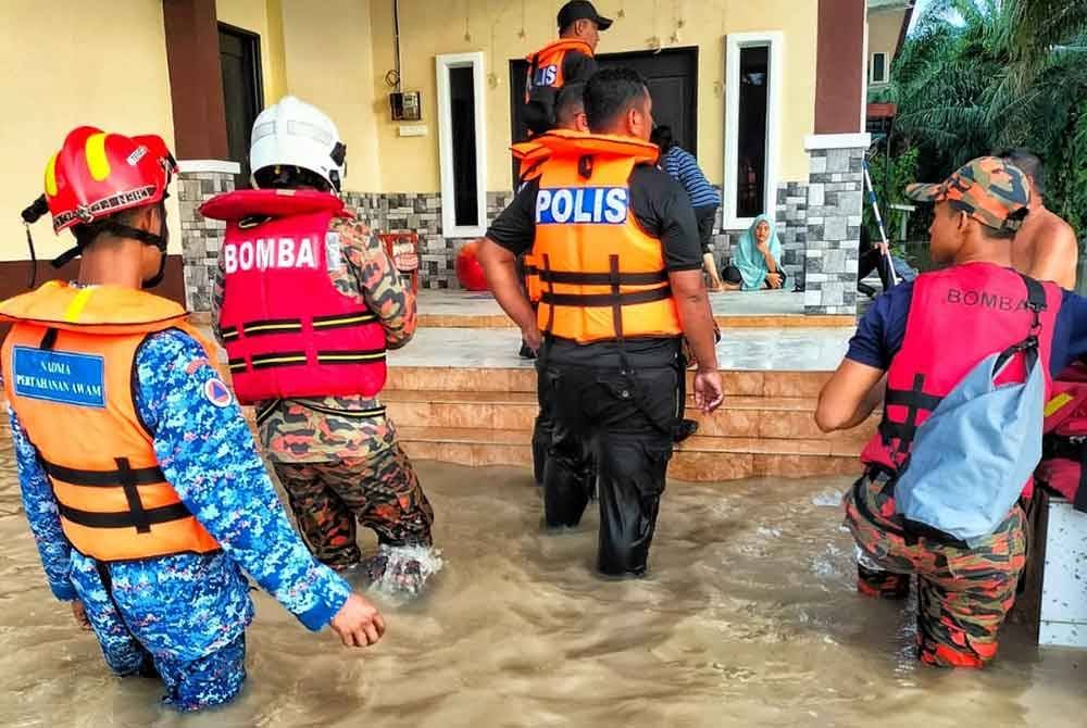 Anggota pasukan keselamatan membantu memindahkan mangsa banjir di daerah Jasin di sini, pada Isnin.