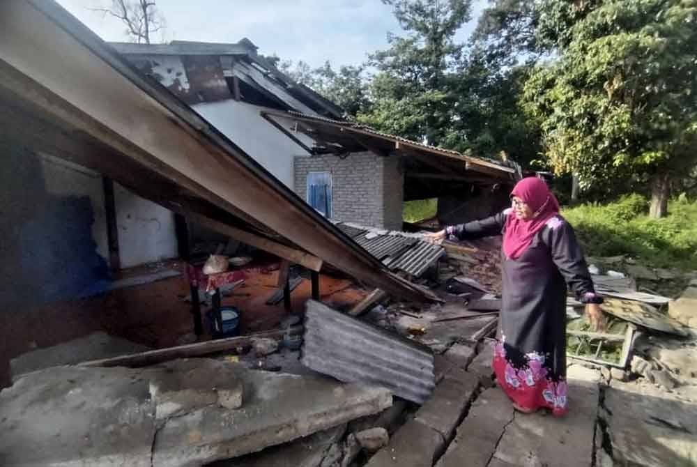 Rukiah menunjukkan bahagian atap dan dinding dapur rumahnya yang runtuh dalam kejadian di Kampung Pak Kancil Dalam, di Setiu.