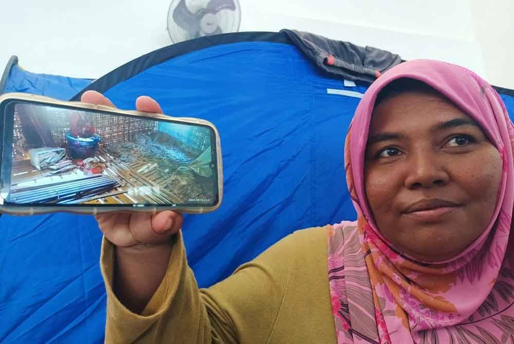 Zalinah menunjukkan keadaan rumah buluhnya yang rosak akibat banjir melanda pada Ahad.