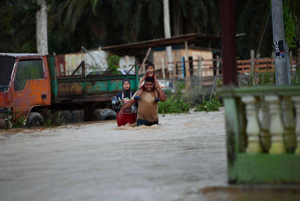 Penduduk meredah air banjir di Kuala Slim. Foto Bernama