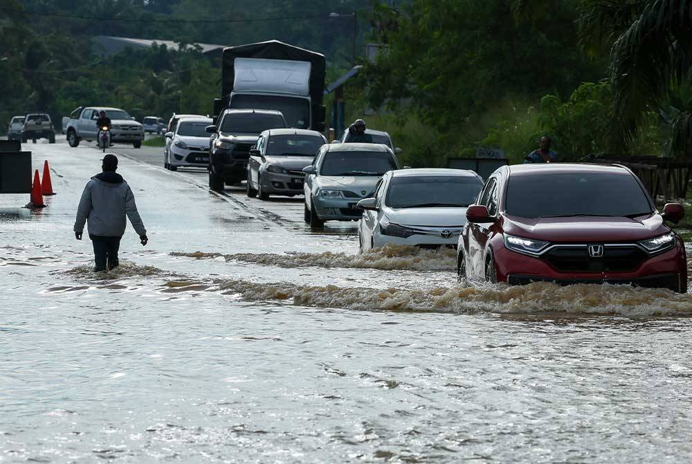 Pemandu memperlahankan kenderaan ketika melalui Jalan Mentakab-Lanchang yang dinaiki air akibat banjir ketika tinjauan hari ini. - Foto: Bernama