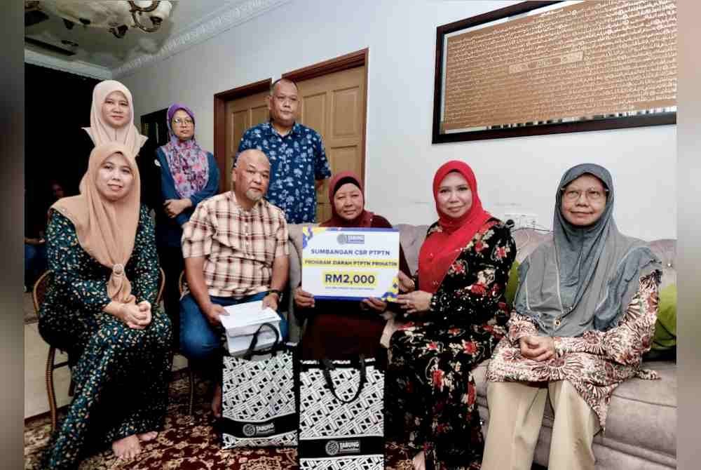 Norliza (dua dari kanan) menyerahkan replika kad sumbangan CSR PTPTN kepada ibu Allahyarham Khairil Anwar, Normah Mohamed Nor (tiga dari kiri) semasa Program Ziarah PTPTN Prihatin di kediamannya di Ampang, Selangor pada Selasa.