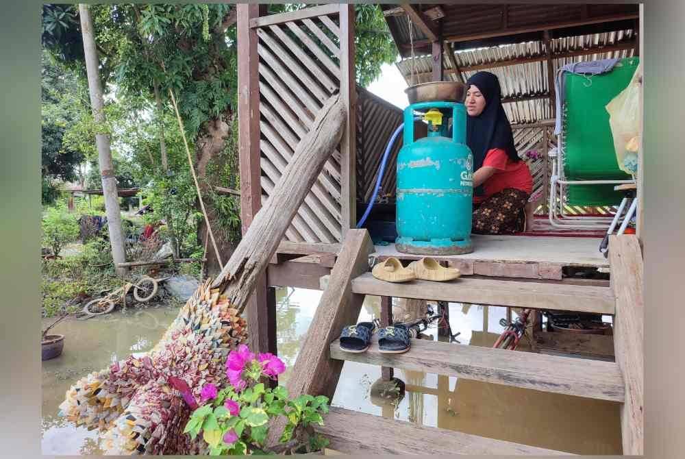 Azrin terpaksa memasak di beranda akibat bahagian dapur ditenggelami air di Kampung Alor Gunung pada Ahad.