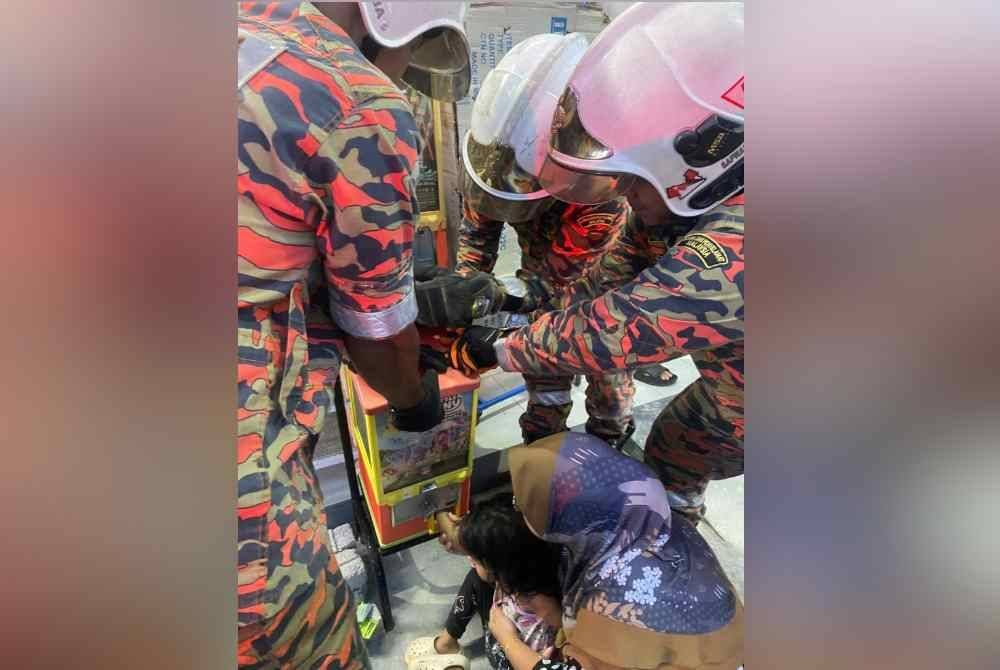 Pasukan bomba menjalankan operasi mengeluarkan tangan mangsa yang tersepit pada mesin permainan di Pantai Remis. Foto Ihsan JBPM Perak