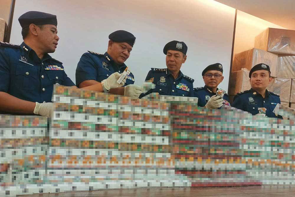 Abdul Ghafar (tengah) menunjukkan hasil rampasan rokok disyaki seludup dalam sidang akhbar pada Khamis.