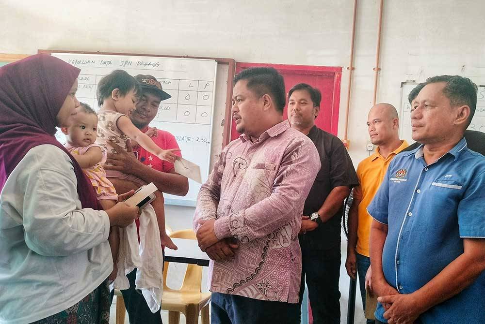 Mohd Hasbie (tengah) menyantuni mangsa banjir di PPS SMK Seri Semantan.