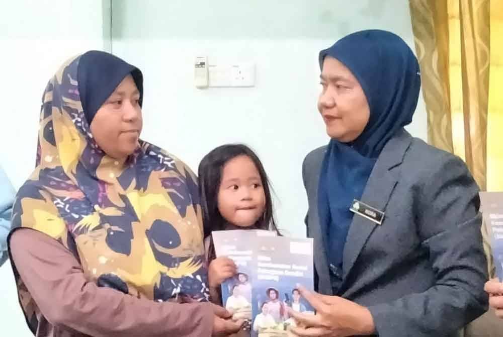 Nora (kanan) menyantuni Siti Nor Zuriati di Kampung Aur Tanjung.