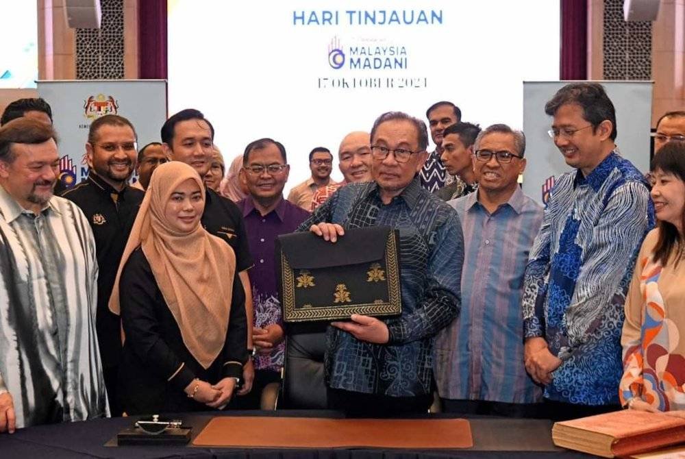 Anwar (tengah) menunjukkan beg fail yang mengandung dokumen Belanjawan 2025 diperbuat daripada songket tenun Kelantan.