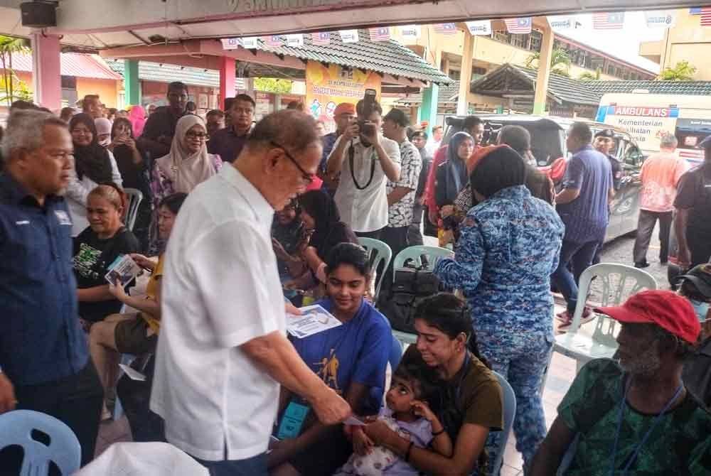 Wan Rosdy (tengah) menyampaikan sumbangan kepada mangsa banjir di PPS SK Mentakab pada Khamis.