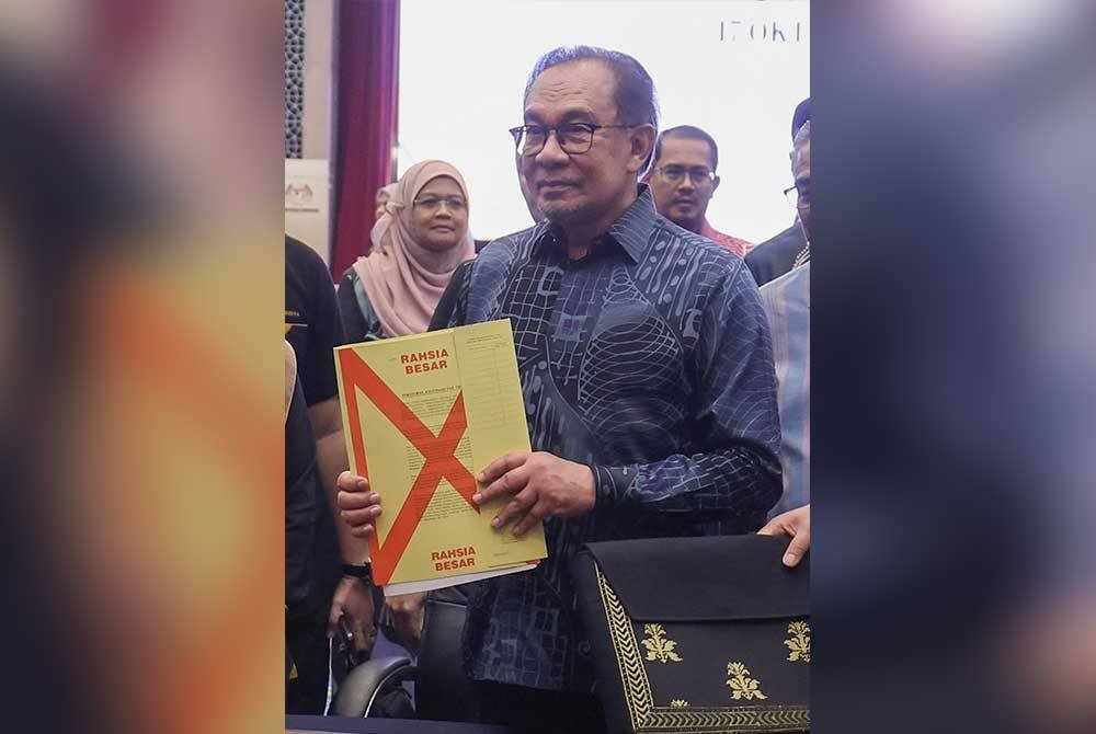 Anwar menunjukkan dokumen Belanjawan 2025 ketika hadir meninjau persiapan penyediaan Belanjawan 2025 di Kementerian Kewangan. Foto Bernama