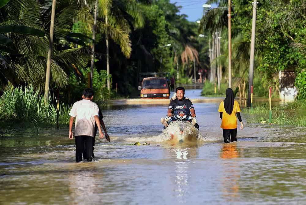 Penduduk melalui jalan yang dinaiki air berikutan fenomena air pasang besar dan pelepasan air di Empangan Chenderoh di Kampung Pasir Garam, Pulau Tiga Kiri. Foto Bernama