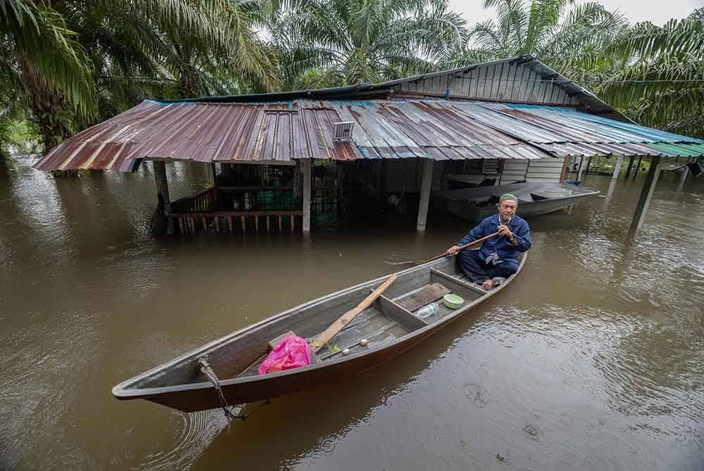 Penduduk setempat mengawasi rumah kediamannya yang terjejas akibat banjir ketika tinjauan di sekitar daerah Hilir Perak. Foto Bernama