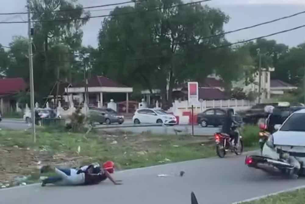 Tangkap layar memaparkan penunggang motosikal yang melakukan aksi &#039;wheelie&#039; sambil membonceng seorang wanita sehingga terjatuh dan kemudian terlanggar hadapan sebuah kereta.