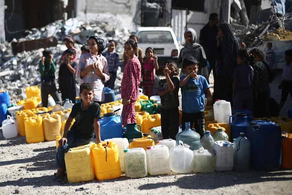 Rakyat Palestin beratur untuk mengisi air berhampiran Khan Yunis di selatan Semenanjung Gaza. Foto AFP