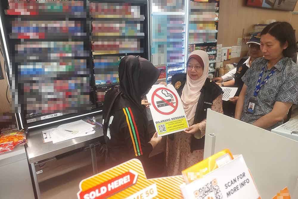 Dr Kasemani memberi papan tanda larangan merokok kepada pekerja kedai serbaneka.