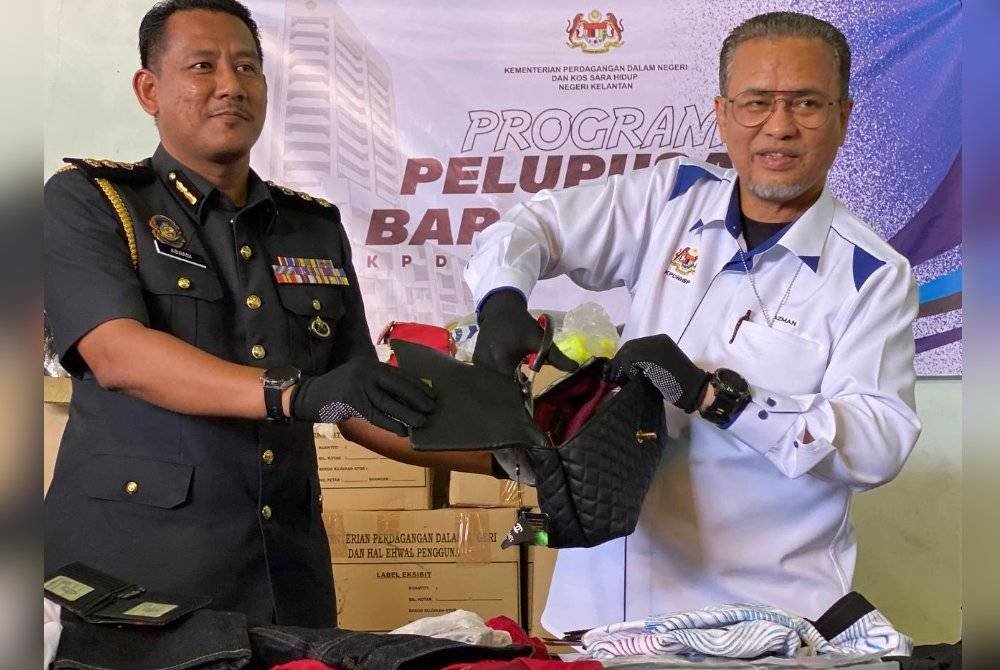 Azman (kanan) menggunting beg tangan ketika Program Pelupusan Barang Kes di stor penyimpanan KPDN di Kandis, Bachok pada Selasa.