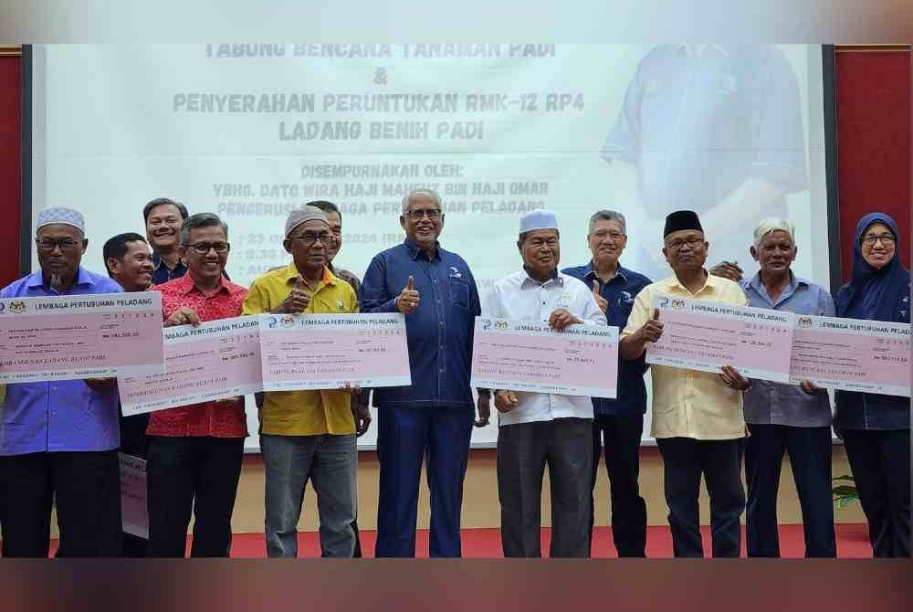 Mahfuz (tengah) bersama sebahagian wakil penerima bantuan tabung bencana tanaman padi yang rosak akibat kemarau di Alor Setar.