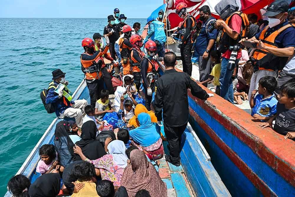 Penduduk tempatan menurunkan pelarian Rohingya dari sebuah bot Labuhan Haji di wilayah Selatan Aceh. Foto AFP