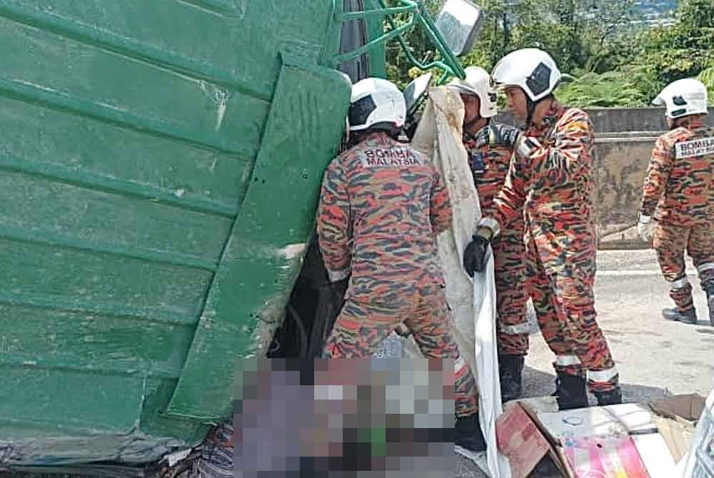 Bomba mengeluarkan pemandu lori daripada lori yang terbalik dalam nahas melibatkan sebuah lori muatan batu serta kereta di Jalan Gua Musang-Lojing pada Jumaat.. - Foto Ihsan Bomba