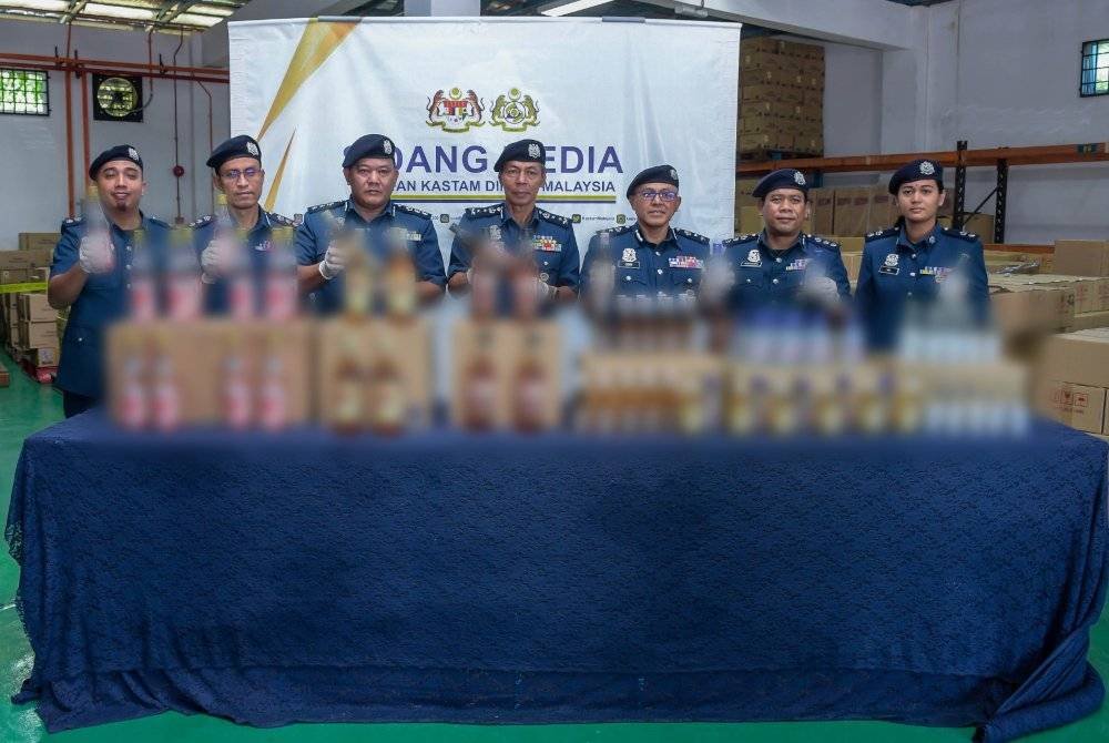 Abdul Ghafar (tengah) menunjukkan kejayaan pasukannya menumpas kegiatan penyeludupan minuman keras dianggarkan bernilai RM2.8 juta di Kuala Lumpur dan Ipoh. Foto ihsan JKDM