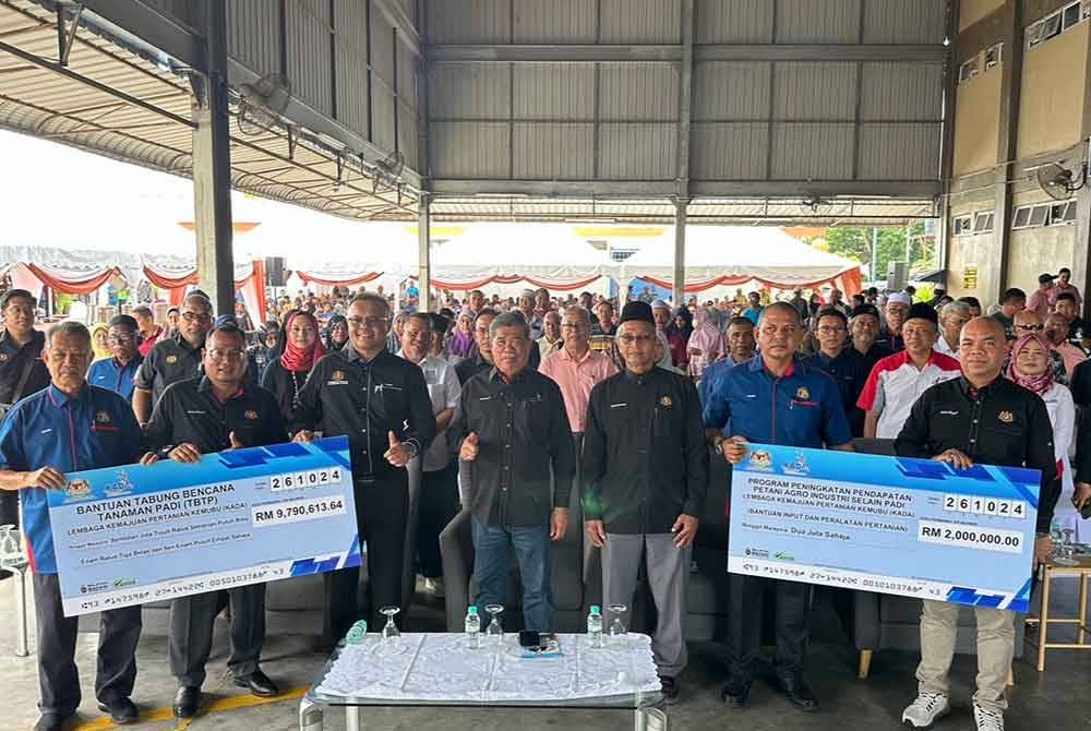 Mohamad (tengah) bergambar bersama pesawah selepas menyampaikan replika cek Tabung Bencana Tanaman Padi dan Bantuan Khas Sumbangan Tunai Kepada Pesawah Fasa 1 di Pertubuhan Peladang Kawasan Nilam Puri pada Sabtu.