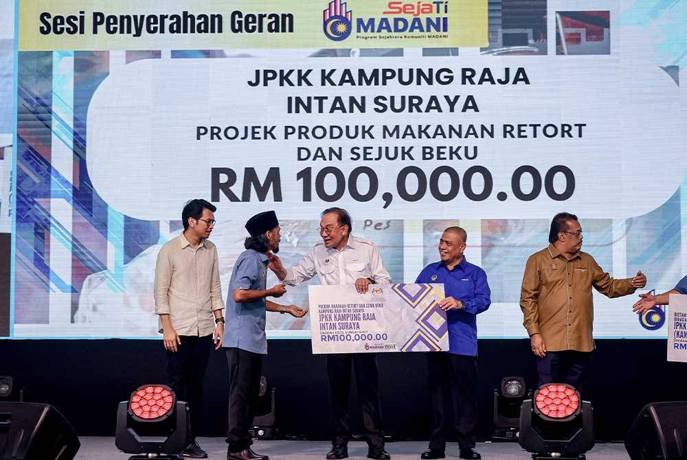 Anwar (tiga, kanan) menyampaikan geran Sejati Madani kepada penerima pada Majlis Ramah Mesra Perdana Menteri Bersama Masyarakat Padang Rengas di Arena Square Pekan Isnin pada Ahad. Foto Bernama