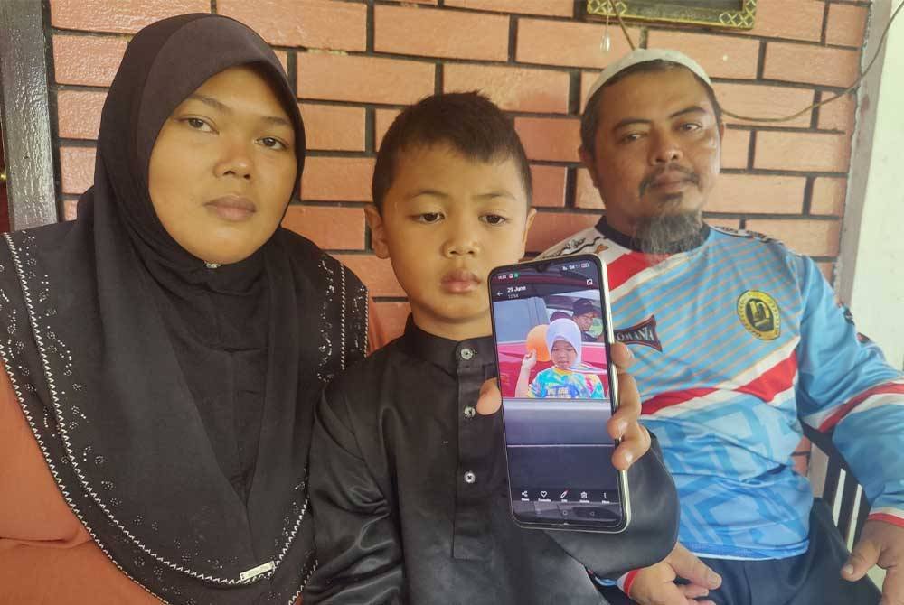 Haslam bersama isteri dan anak sulungnya menunjukkan gambar arwah di rumahnya di Kampung Sungai Kajang Lama, Tanjong Karang, di sini pada Ahad.