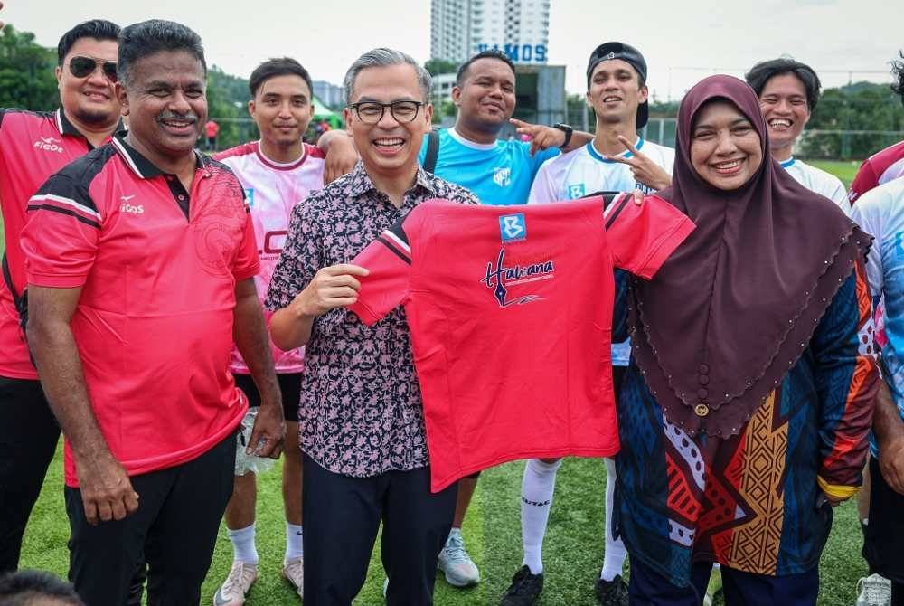 Fahmi (tengah) menerima jersi daripada Nur-ul Afida (kanan) dan Arul Rajoo (kiri) pada Kejohanan Bola Sepak 9 Sebelah (9s) dan Bola Jaring Antara Media sempena Sukan Hawana di Brainy Bunch Melawati pada Ahad. Foto Bernama