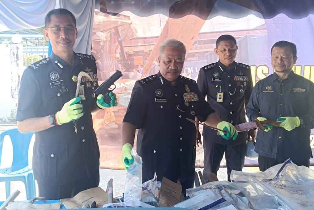 Mohd Khairi (kiri) menunjukkan barang kes yang akan dilupuskan ketika Majlis Pelupusan Barang Kes Jenayah di pekarangan Ibu Pejabat Polis Kontinjen Terengganu pada Isnin.