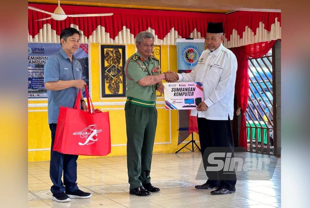 Mardzuki (tengah) menyampaikan sumbangan komputer riba kepada SK To’ Uban yang diwakili Guru Besar, Sanusi Jaafar (kanan). Foto Sinar Harian ADILA SHARINNI WAHID