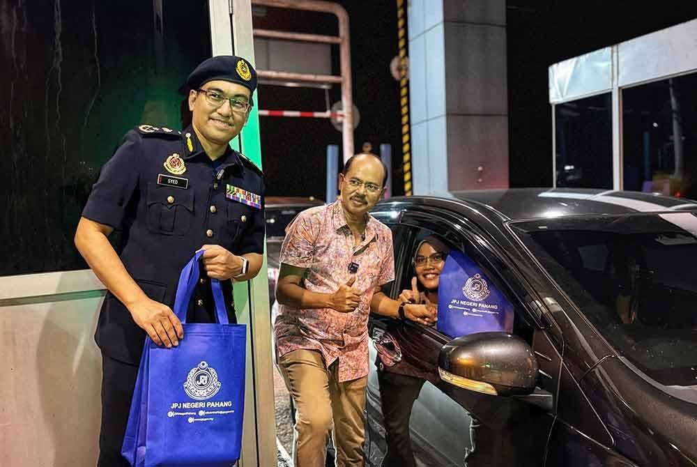 Razali (tengah) bersama Syed Ahmad menyantuni pengguna di Plaza Tol Gambang pada Rabu.
Foto ihsan JPJ Pahang