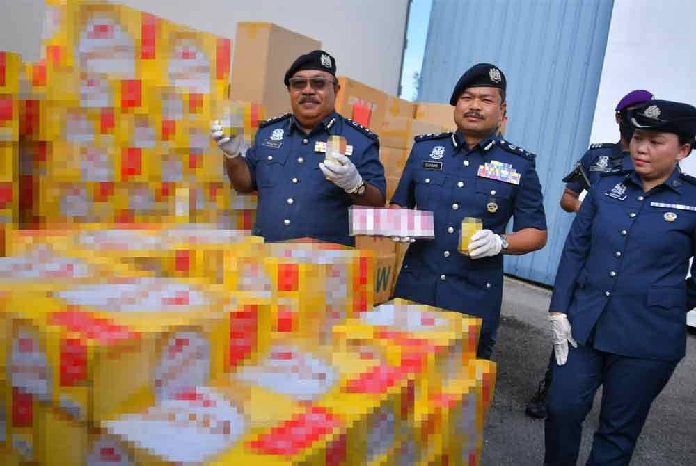 Norizan (tengah) menunjukkan minuman keras yang disorok dałam lori pada sidang media di Stor Bahagian Penguatkuasaan Kuching JKDM pada Jumaat. Foto Bernama