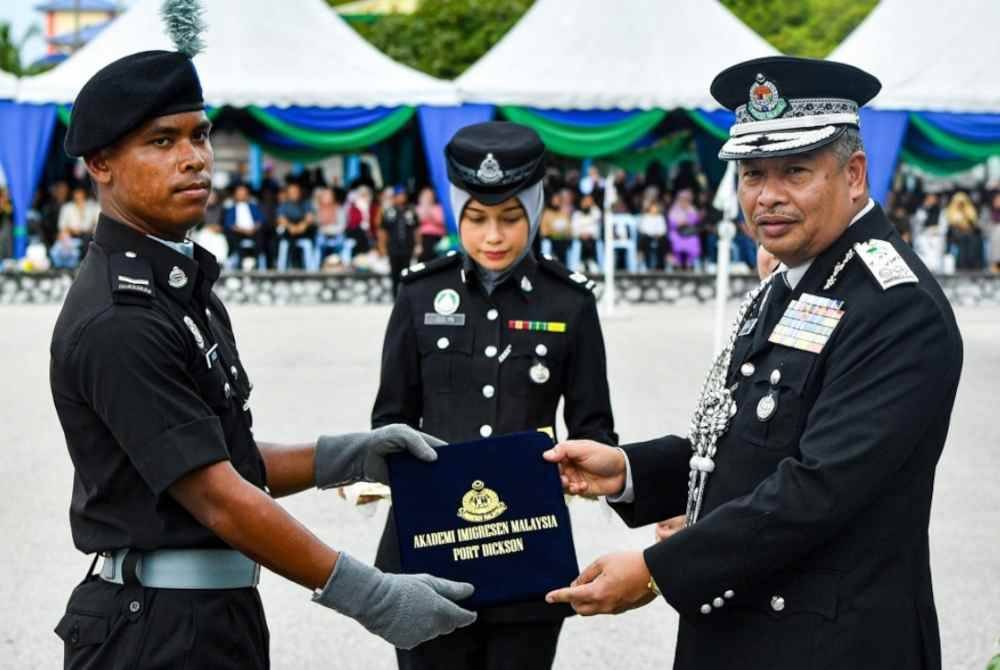 Zakaria (kanan) menyampaikan Anugerah Keseluruhan Terbaik kepada Kadet Pegawai Imigresen, Mohd Nazmi Nor Sham (kiri) pada Majlis Perbarisan Tamat Latihan Kursus Sijil Asas, Tinggi dan Pengurusan Keimigresenan Siri 1 Tahun 2024 di Akademi Imigresen Malaysia, pada Sabtu. Foto Bernama