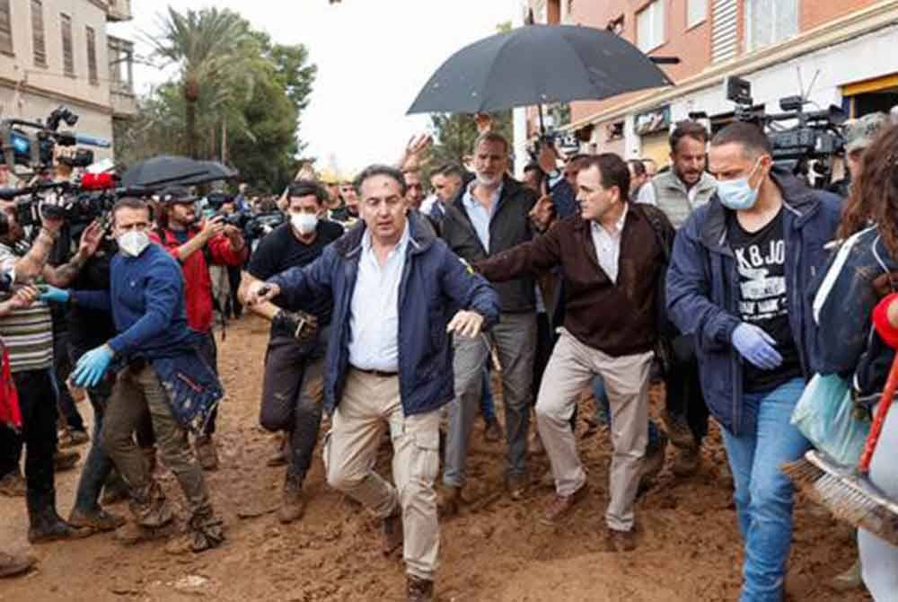 Raja Felipe VI (berpayung) dilindungi oleh anggota pasukan keselamatan selepas baginda dilemparkan dengan lumpur dan telur semasa berangkat meninjau mangsa banjir di Paiporta, Valencia pada Ahad. Foto Reuters