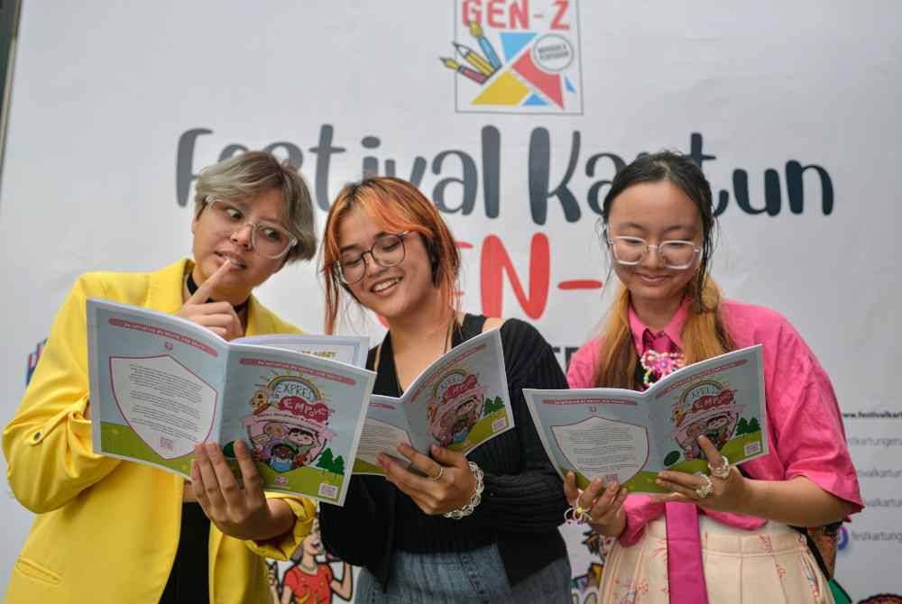 Ain Husniza bersama dua rakannya, Iqsa Aqilah (kiri) dan Karyn Ngiam (kanan) melihat buku kartun berjudul Express to Empower ketika pameran Festival Kartun Gen Z di Rumah Tangsi, baru-baru ini. Foto Bernama