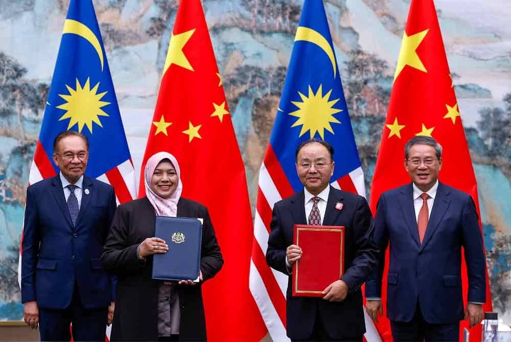 Anwar (kiri) dan rakan sejawatannya, Li Qiang (kanan) menyaksikan pertukaran Memorandum Persefahaman (MoU) antara Bernama dan Kumpulan Media China (CMG) - Foto: Bernama