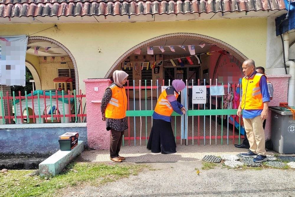 Halyjah (dua,kanan) mengunci taska haram yang beroperasi di Batu Berendam di sini, pada Rabu.