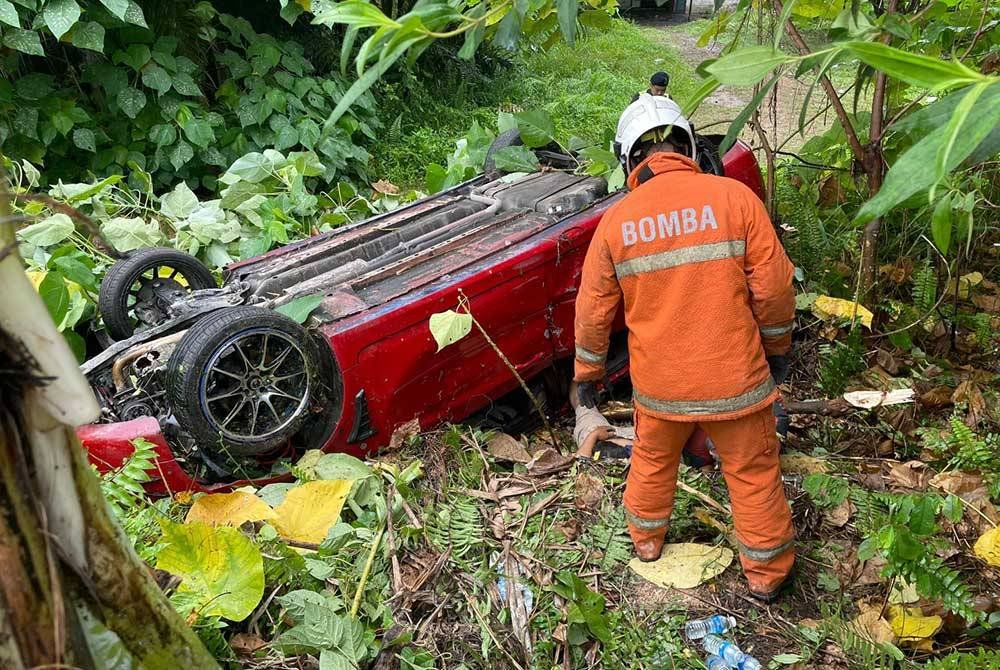 Anggota bomba melakukan kerja-kerja membantu mengeluarkan mangsa tersepit selepas kereta Proton Persona dipandu terbabas di Jalan Kuala Selangor, Kampung Merbau Indah di sini pada Jumaat.