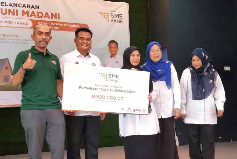 Mohammad Hardee (kiri) dan Zahari (dua dari kini) menyerahkan sumbangan Back To School pada Majlis Pelancaran Program Santuni Madani di Dewan Hassan Abdullah, Kampung Pasir Johor Bahru, pada Ahad.