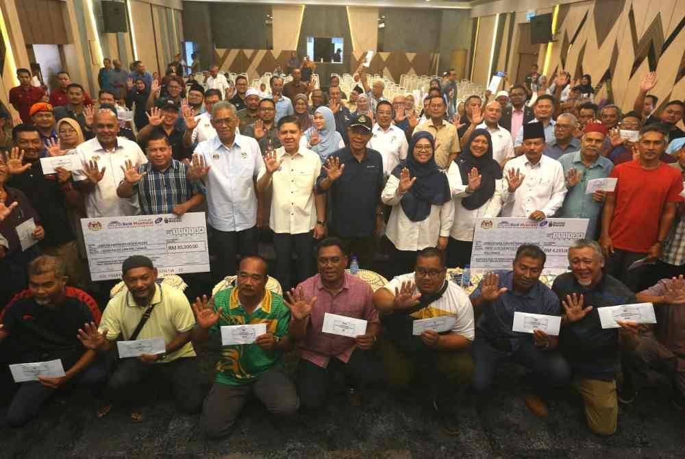 Saifuddin (tengah) dan Ismail (empat dari kiri) bergambar bersama sebahagian penerima sumbangan ihsan Perdana Menteri seusai majlis penyerahan.