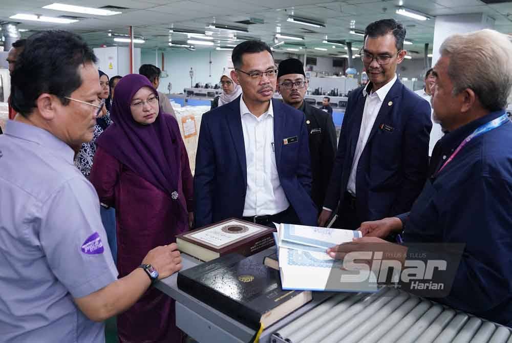 Mohd Fauzi (tengah) mendengar penerangan berkaitan percetakan al-Quran yang dikeluarkan oleh Karangkraf. Foto Sinar Harian-MOHD HALIM ABDUL WAHID