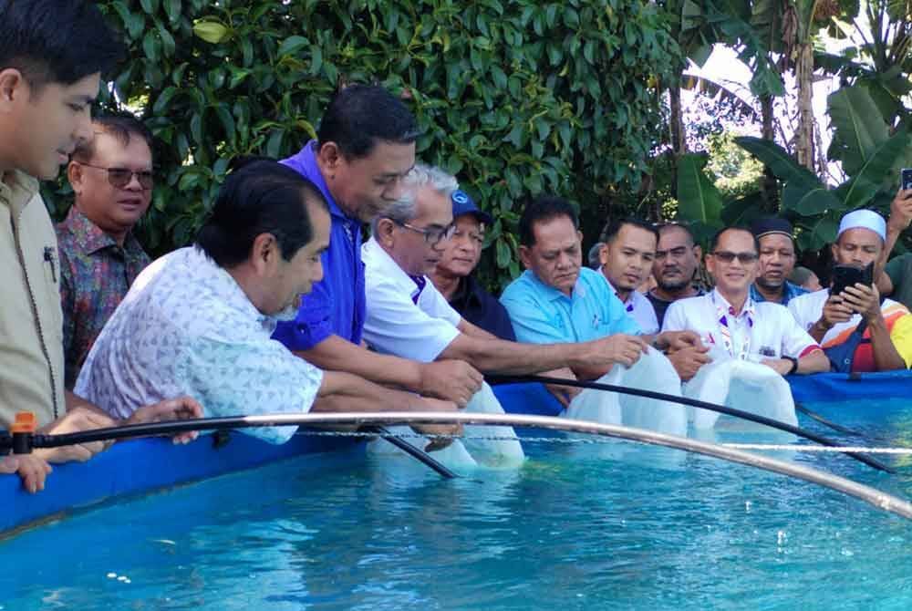 Ahmad Ramzi (lima dari kiri) ketika program pelepasan anak ikan tilapia di Kampung Gong Mak Som, di Besut pada Selasa.