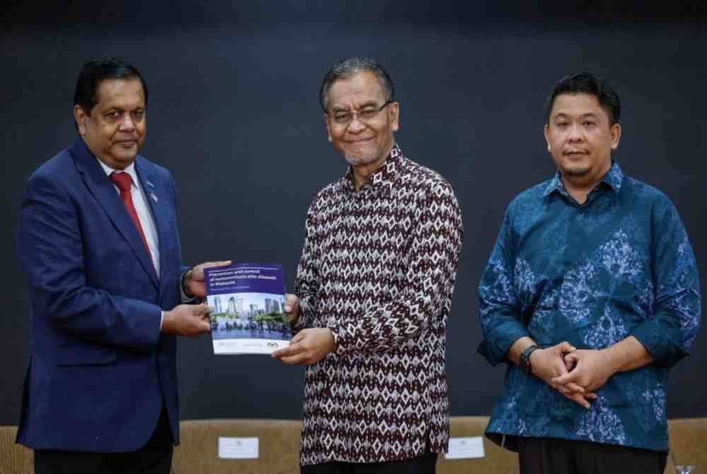 Dr Dzulkefly menerima buku laporan daripada wakil Pertubuhan Kesihatan Dunia (WHO) ke Malaysia, Singapura dan Brunei Dr Rabindra Abeyasinghe (kiri) pada Majlis Laporan Pencegahan dan Kawalan Penyakit Tidak Berjangkit (NCD) di Malaysia dan Taklimat Penguatkuasaan Akta 852 dan Inisiatif Kesihatan Paru-Paru Kebangsaan 2025-2030 kepada ahli Parlimen di bangunan Parlimen, pada Khamis. Foto Bernama