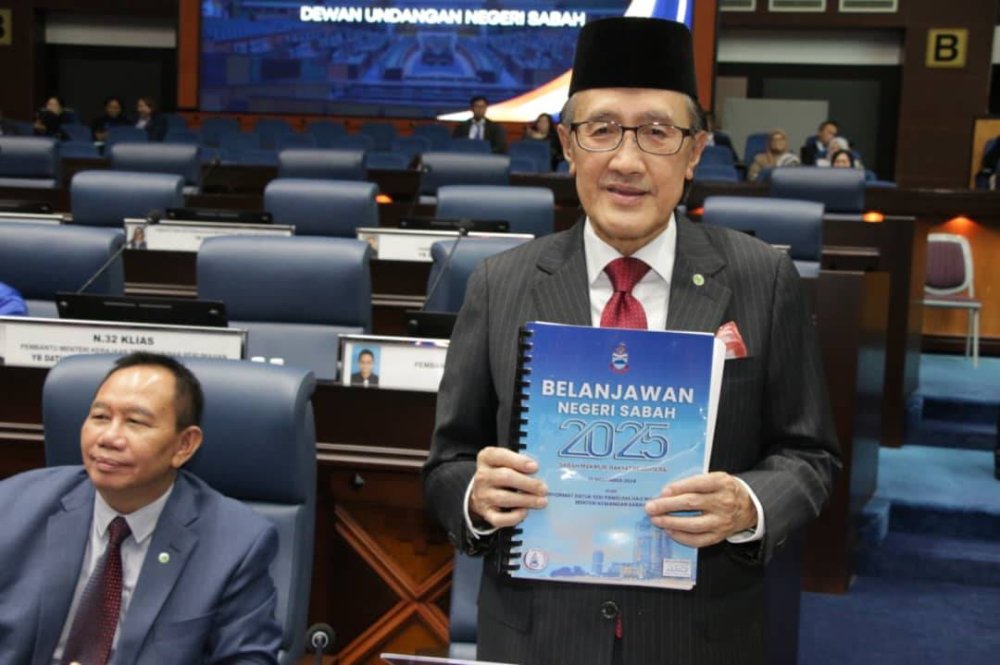 Masidi menunjukkan Belanjawan Kerajaan Negeri Sabah 2025 sebelum membuat pembentangan di DUN Sabah, pada Jumaat. 